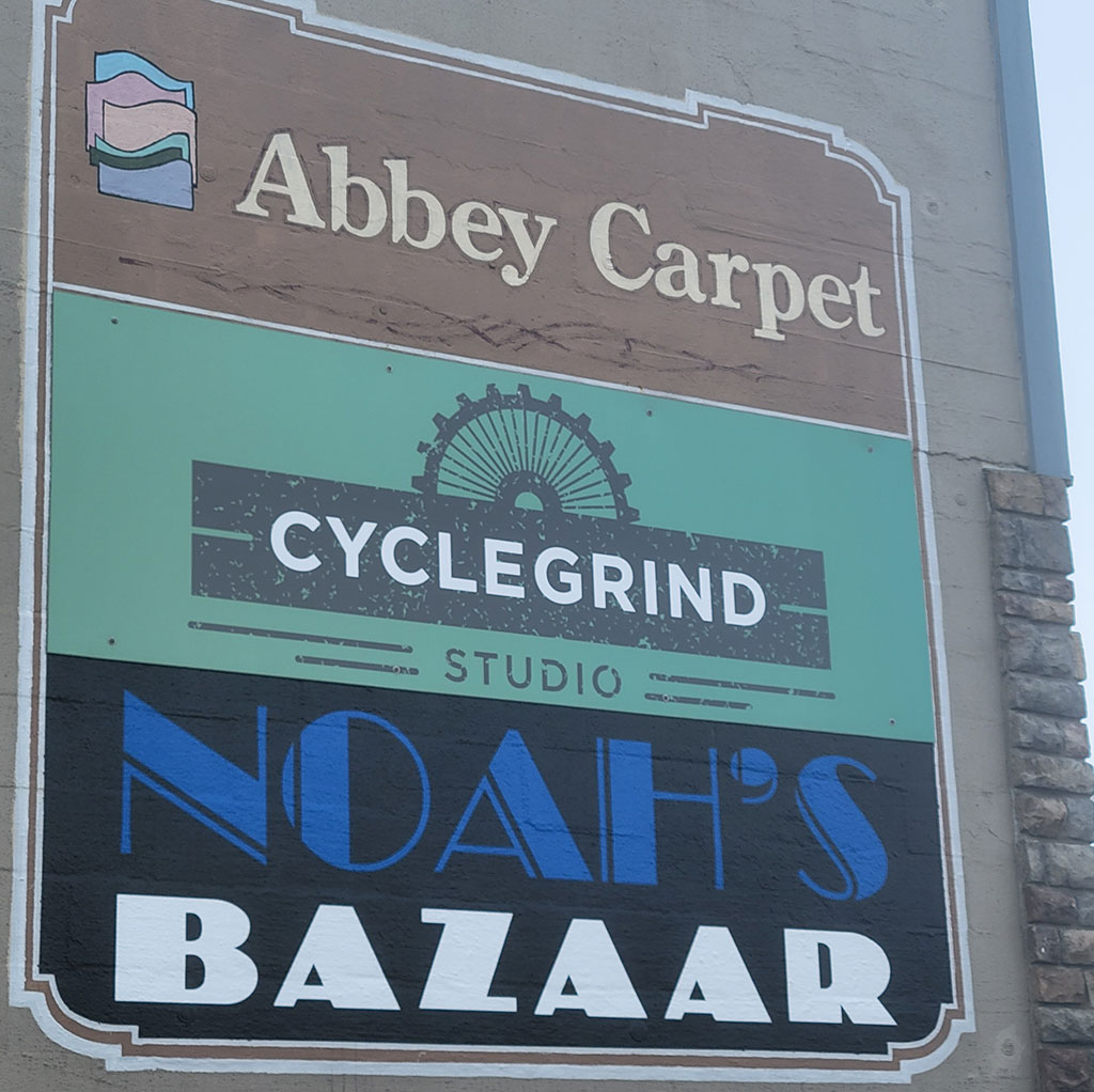 street signage: Abbey Carpet - CycleGrind Studio - Noah's Bazaar - Newport, Oregon